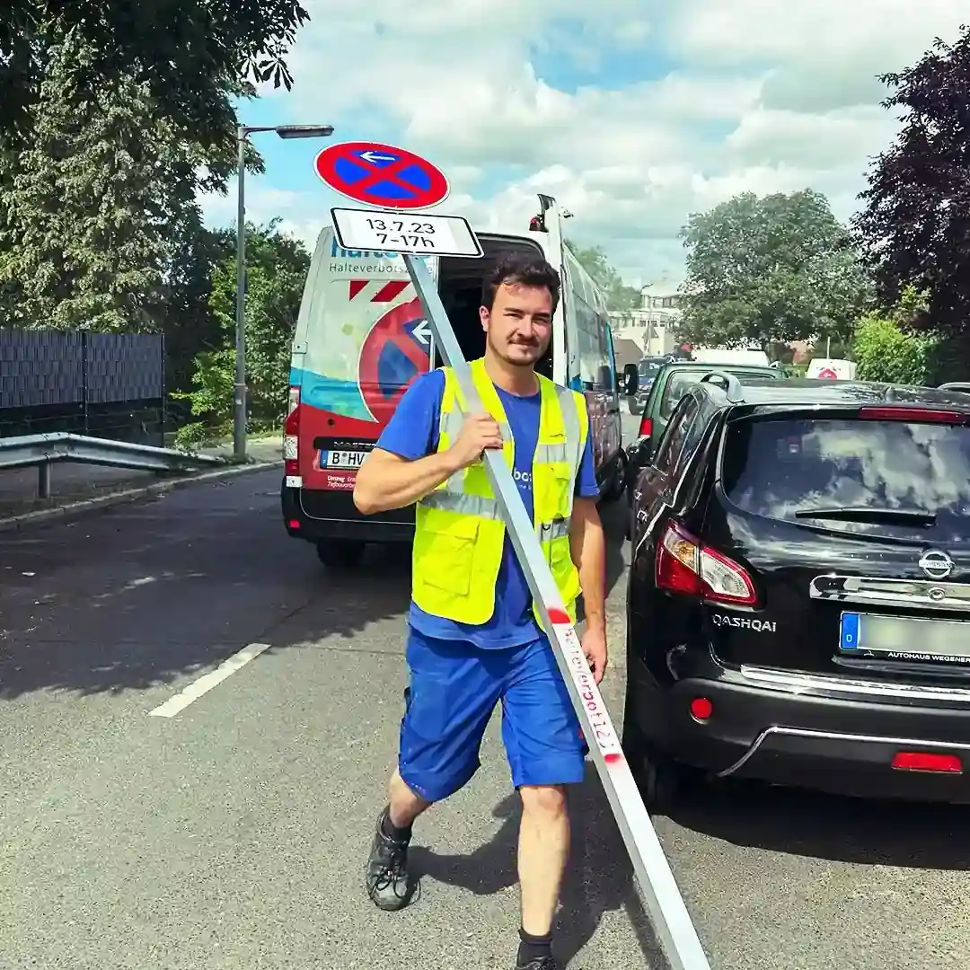 Mitarbeiter transportiert Halteverbotsschild